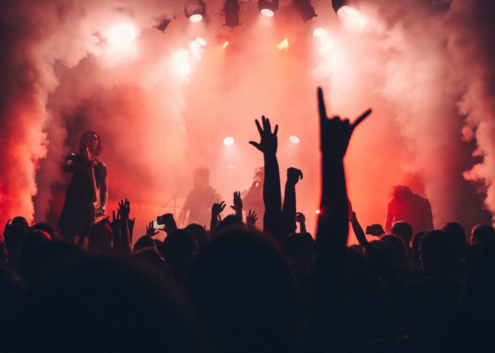 Silhouette of crowds at a concert against pale orange smoke